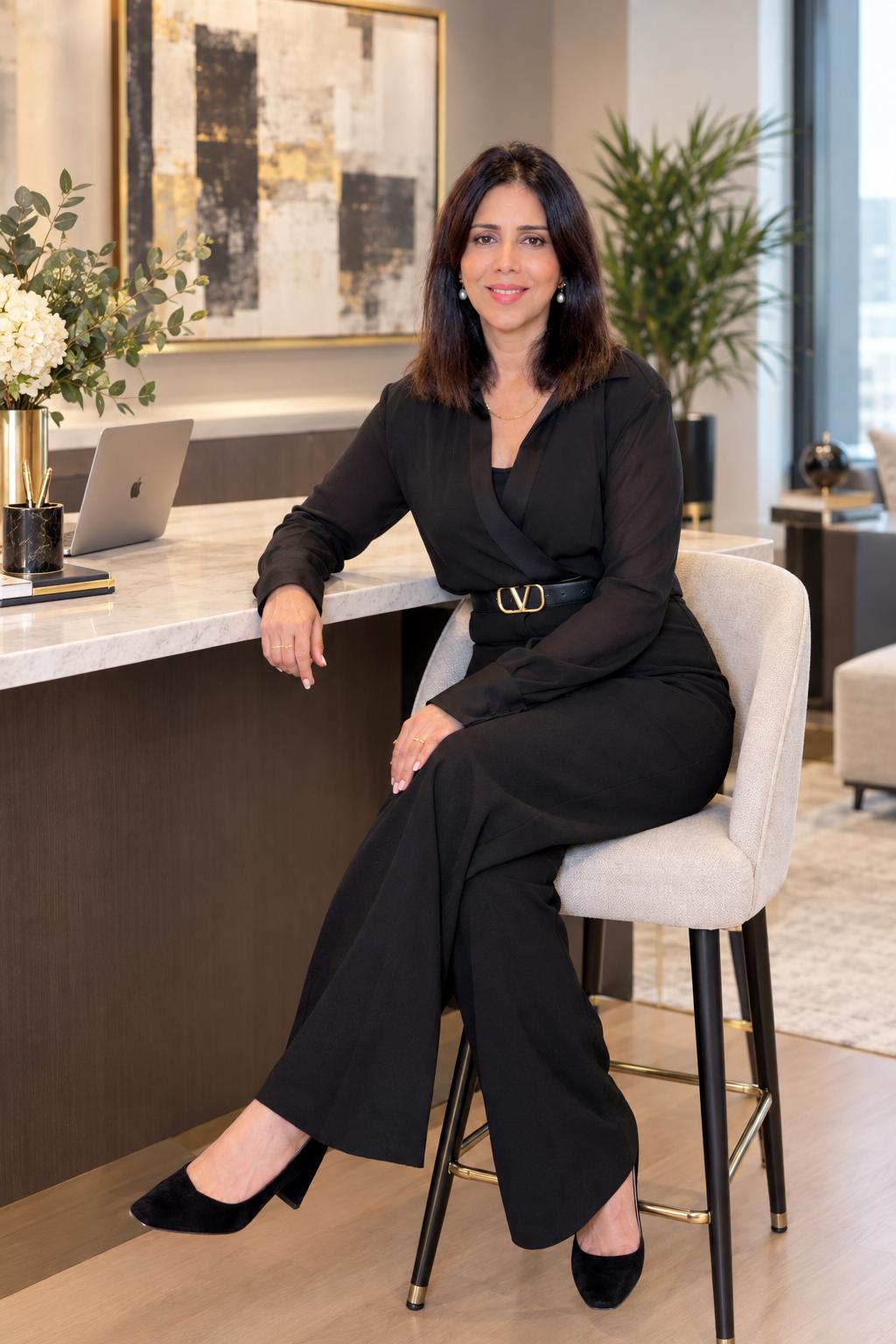 Naveeda Rana seated in her office in a black outfit
